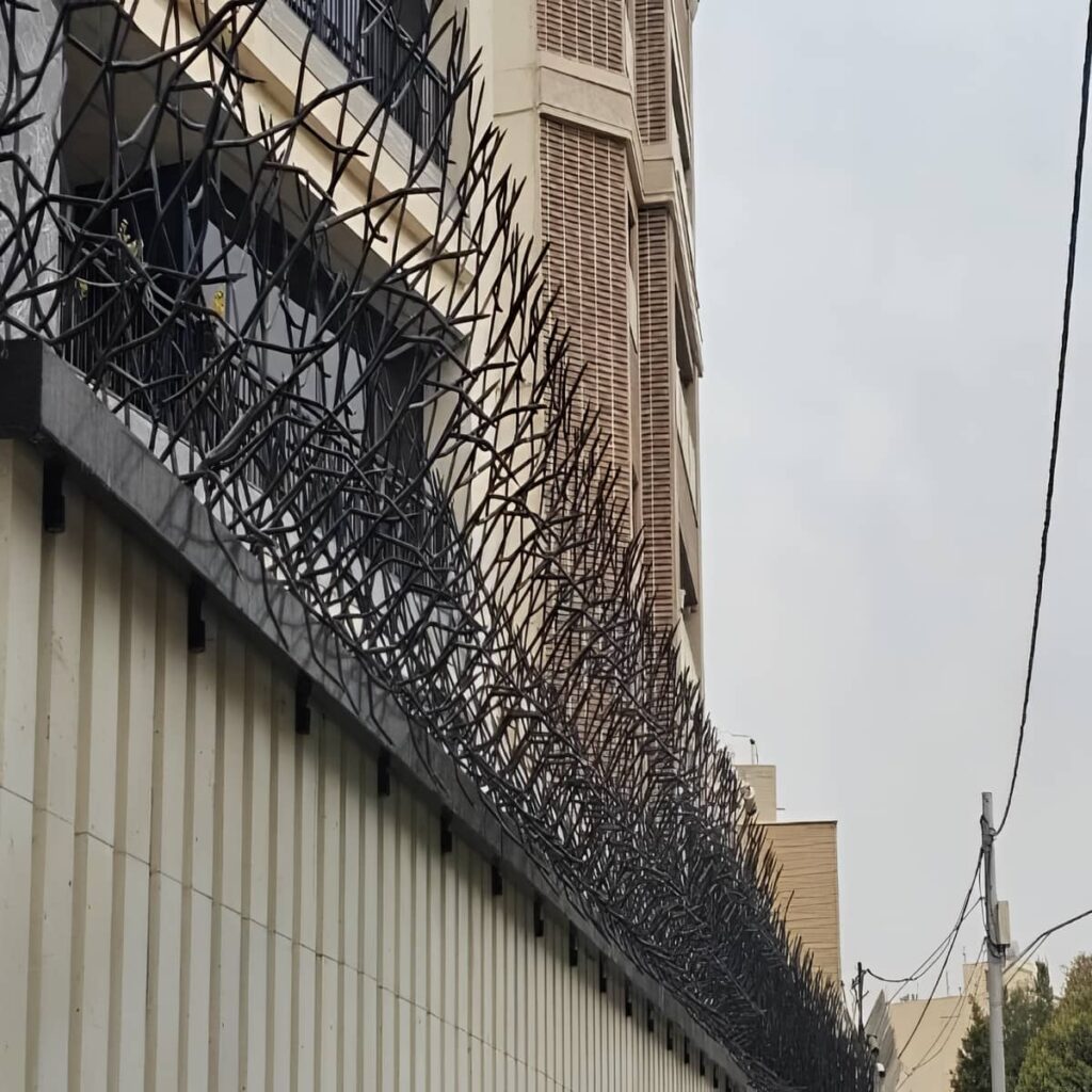 نرده سرنیزه‌ای فلزی روی دیوار سنگی همدان