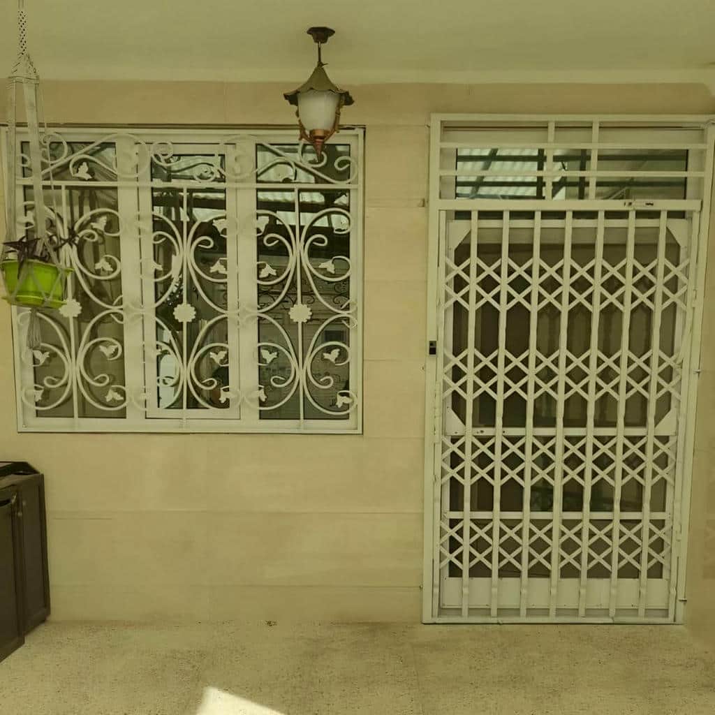 گارد آکاردئونی سفید کنار درب باغ در ارومیه